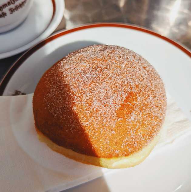 A fried doughnut with grains of sugar on its surface